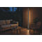 Stehlampe beleuchtet Wohnzimmer bei Nacht. Sofa, Sessel, Tisch und Pflanzen. Warme Atmosphäre.