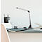 Une lampe de bureau argentée est sur un bureau. Une tasse, des cahiers et du papier sont également sur le bureau.