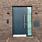 Porte d'entrée anthracite moderne avec partie vitrée et numéro de maison sur un mur de briques.