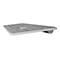 Seitenansicht einer flachen, silbernen Computertastatur mit grauen Tasten auf weißem Hintergrund.