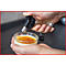 Person flambiert Crème brûlée mit einem Küchenbrenner. Das Dessert befindet sich in einem Glas.