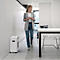 A woman walks past a paper shredder in a modern office.