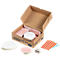 Open brown box with workshop material. Includes: paper, adhesive dots, round cards, and a white container.