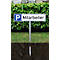 Parking sign 'Employees' in front of green plants. The sign is on a metal pole. The tip of the pole is anchored in the ground.