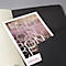 A black notebook with a flyer partially covered. The flyer reads "RED CONCE...".