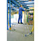 Man stands on a platform ladder and works in a factory. Materials and machines can be seen in the background.