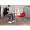 Mann am Tisch, schreibt. Roter Stuhl, Tisch mit Getränken. Helles Büro.