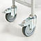 Close-up of two casters with brakes, mounted on a metal frame. The casters are gray, the frame parts are silver.