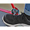 Gros plan : Chaussure noire sur une construction métallique rouge avec ressort et repose-pieds.
