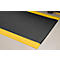 Black mat with yellow edges lies on light floor. The surface is dotted.