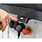 Close-up van een hand die een bedieningspaneel met een digitale display bedient. Hieronder bevinden zich stopcontacten en een rode noodstopknop.