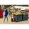 A woman pulls blue wooden crates with a red forklift in a supermarket. The crates are filled with goods.