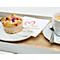 Un muffin aux framboises est posé sur une assiette à côté d'un café. Une serviette avec un cœur et des vœux de bienvenue est posée sur le plateau.