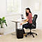 A smiling woman shreds paper at a desk. A black shredder is on the right.