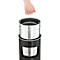 Hand holding a metal container with a handle, inserted into a black cylinder. There is also a metal container inside the cylinder.