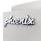 Nahaufnahme des verchromten Phoenix-Schriftzugs auf einer hellgrauen, strukturierten Oberfläche.