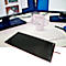 Tapis de souris noir sur le bureau, bord rose, derrière le clavier, tasse, moniteurs.
