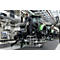 Un homme travaille sur un tracteur dans une usine, debout sur un petit escabeau.