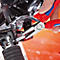 Close-up van een persoon die aan een motorfiets werkt met een rode en blauwe KNIPEX-tang. De tang grijpt een metalen pin.