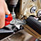 Persoon repareert motorfiets met tang. Tang met rode en blauwe handvat.