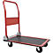 Ein roter Handkarren steht vor weißem Hintergrund. Er hat vier Räder und eine Ladefläche mit schwarzer strukturierter Oberfläche.