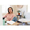 Young woman wearing headphones in a bright apartment, looking intently at a notebook.