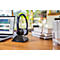 Black headset on stand, laptop and books on wooden surface. A room in the background.