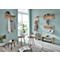 Un couloir peint en bleu clair avec des meubles en bois, dont des porte-manteaux, des tables d'appoint et un banc. Des plantes et une valise complètent l'ameublement.
