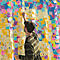 Un homme écrit sur un post-it jaune sur un mur recouvert de notes colorées. En arrière-plan, inscriptions.