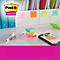 Post-it-Haftnotizen auf Schreibtisch. Gelbe, orange, grüne und pinkfarbene Zettel; daneben Stifte und Handy.