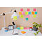 Bureau met lamp, klok, plakbriefjes en plant. Verschillende plakbriefjes met handgeschreven notities op de muur.