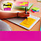 Persoon schrijft met een pen op een gele Post-it-briefje dat op een laptop geplakt zit. Meer post-it-briefjes in de buurt.