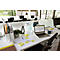 Bureau de bureau avec ordinateur portable, post-it, tasse et plante. En arrière-plan, d'autres postes de travail.