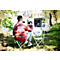 Ein Mann sitzt mit einem Smartphone an einem Campingtisch am See und nutzt eine tragbare Powerstation.