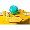 Table jaune avec décorations de fête : assiettes, gobelets, ballon. Des bonbons colorés sont dispersés.