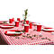 Une table est dressée avec une nappe à carreaux rouges. Des assiettes, des gobelets, des bougies et des branches vertes sont sur la table.
