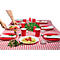 Une table dressée avec une nappe à carreaux rouges et blancs, des assiettes de nourriture, des gobelets rouges et des bougies, une main posant une assiette.