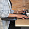 Person working with a black elbow cushion and ergonomic mouse. She is wearing a blazer.