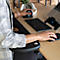 Person working at desk, operating ergonomic mouse and keyboard, arm rest.
