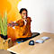 Smiling woman stretching at a desk, ergonomic accessories in front: mouse, keyboard, tray.