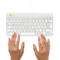 Hände tippen auf einer weißen Tastatur mit gelbem Logo. Der Hintergrund ist weiß.