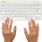 Hände tippen auf eine weiße Tastatur. Buchstaben und Zahlen sind deutlich sichtbar. Das Logo befindet sich oben links.