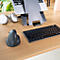 Laptop auf Ständer, ergonomische Maus, Tastatur und Kopfhörer auf einem Holztisch.