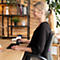 Eine Frau arbeitet mit einer ergonomischen Maus und Tastatur an einem Schreibtisch.