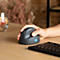Eine Hand bedient eine ergonomische vertikale Maus auf einem Schreibtisch neben einer Tastatur.