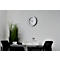 White clock on grey wall, table with teacups and decor.