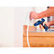 A person is using a blue hot glue gun to attach wood to a wall.