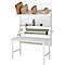 Witte inpaktabel met planken, kartonnen dozen, verpakkingsmateriaal en een tape-dispenser.