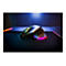 Drahtlose Gaming-Maus mit RGB-Beleuchtung auf schwarzem Mauspad, farbige Lichter. Im Hintergrund ein Laptop.