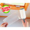 Mains tenant un rouleau anti-peluches Scotch-Brite avec une fenêtre en arrière-plan.